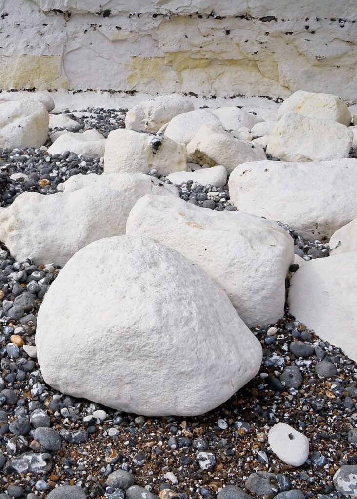 Seven Sisters: los acantilados blancos MÁS IMPRESIONANTES de Inglaterra. boulders on a beach at seven sisters cliffs, east sussex, uk.